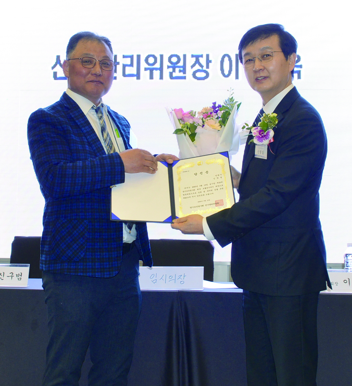 경기도안경사회 신임회장으로 선출된 신영일 회장(오른쪽)이 이동욱 선거관리위원장으로부터 당선증을 전달 받고 기념촬영을 하고 있다.